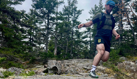 Man running on trail with NNormal Tomir 2 shoes and Black Diamond Distance 15 pack