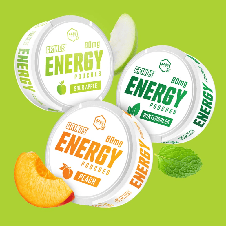 Three cans of Grinds Energy Pouches in Sour Apple, Wintergreen, and Peach flavors on a green background.