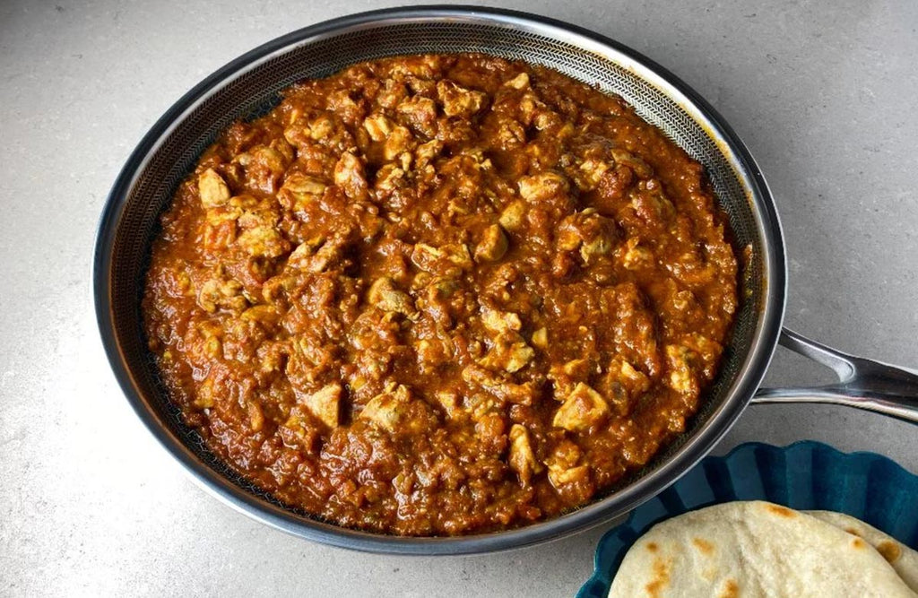 Image of Chicken Karahi, Pakistani chicken stew, in a frying pan with bread