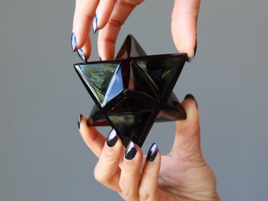 Hands holding Black Obsidian Merkaba