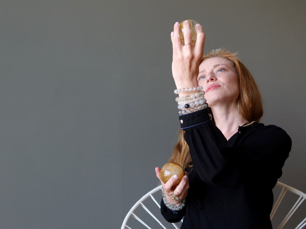 woman holding two golden quartz crystal balls