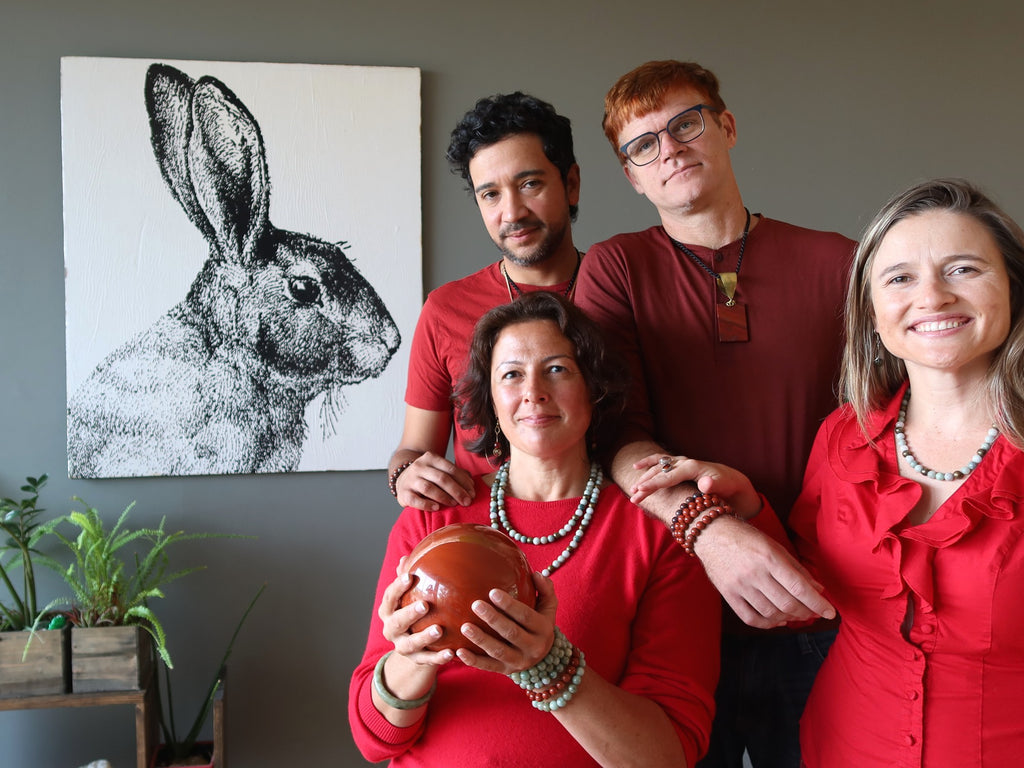 four people dressed in red wearing jade and holding red jasper, rabbit picture on the wall