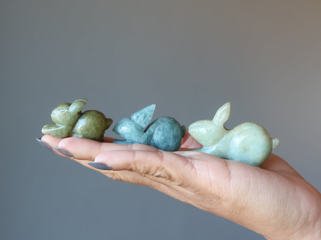 hand holding three green jade rabbits