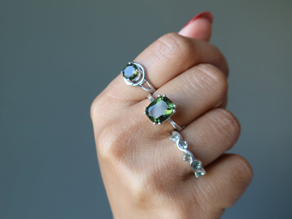 hand wearing three moldaVite rings