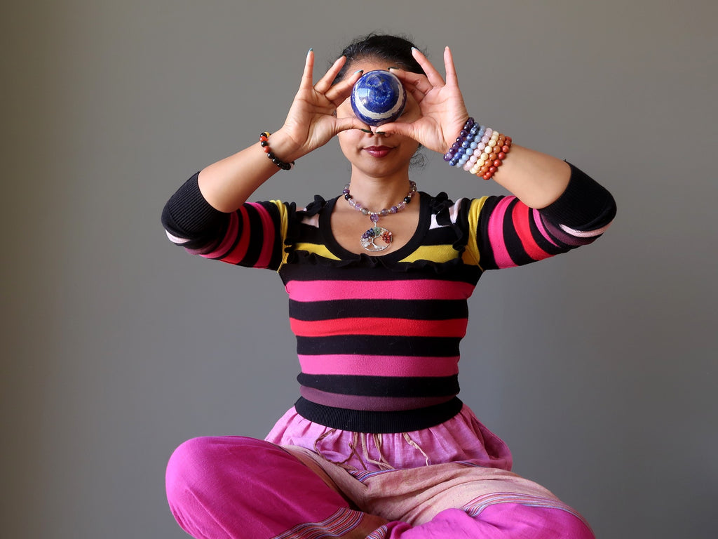 sheila of satin crystals meditating with a lapis lazuli crystal ball at her third eye chakra