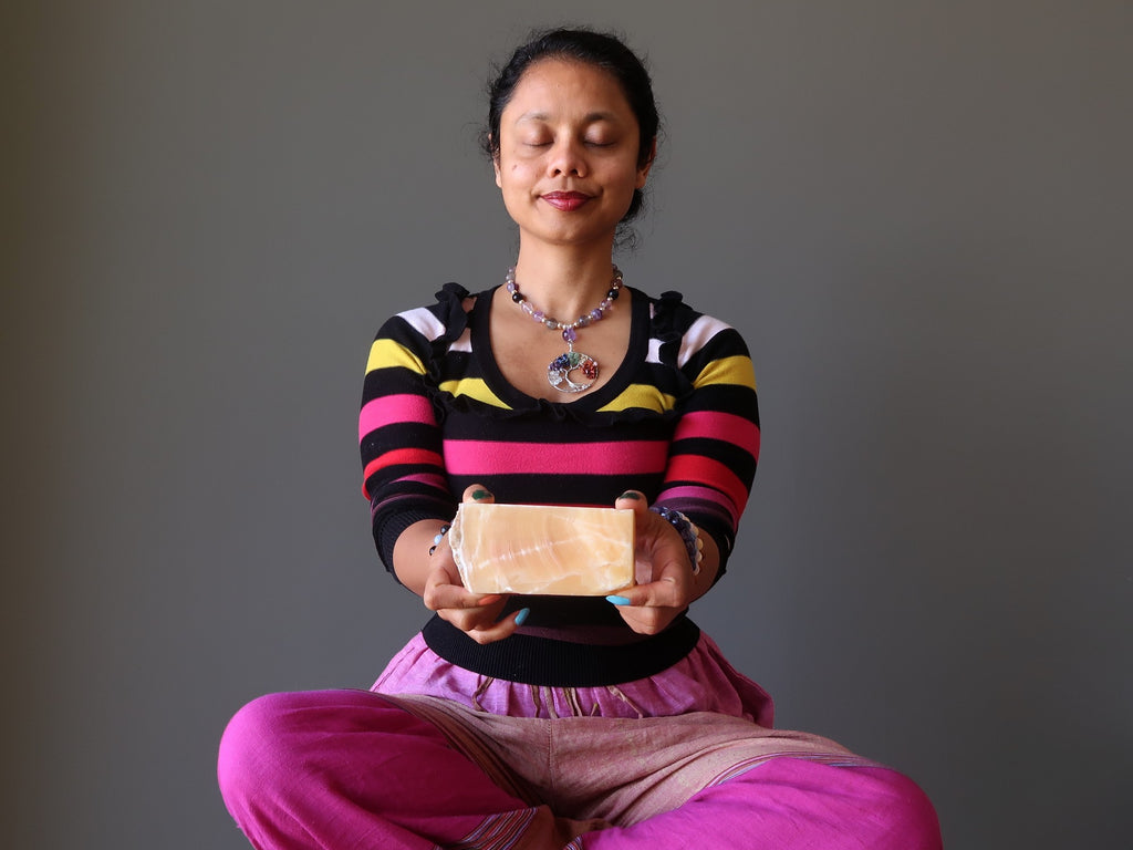 sheila of satin crystals meditating with a yellow calcite block at her solar plexus chakra