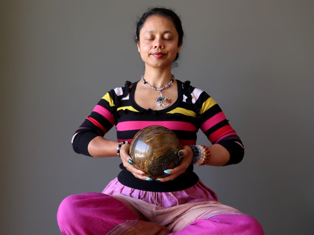 sheila of satin crystals meditating with a large tigers eye sphere