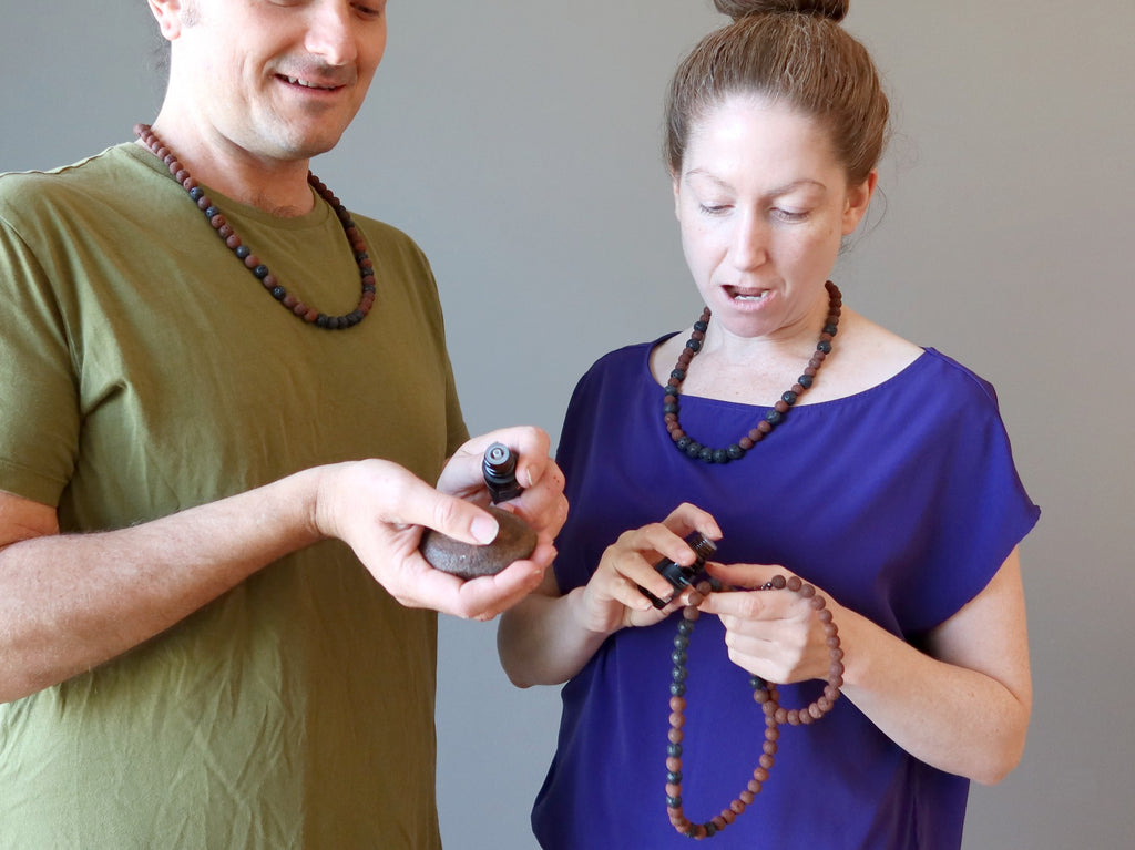 man and women putting essential oil on lava necklaces