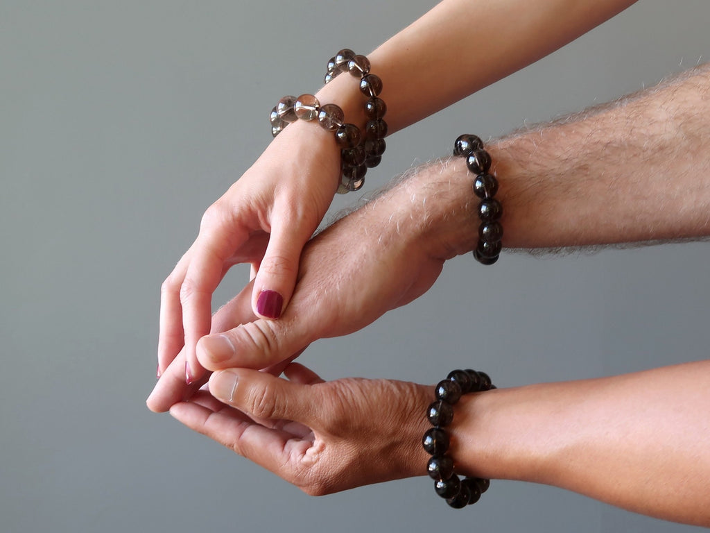 three hands coming together wearing smoky quartz stretch bracelets