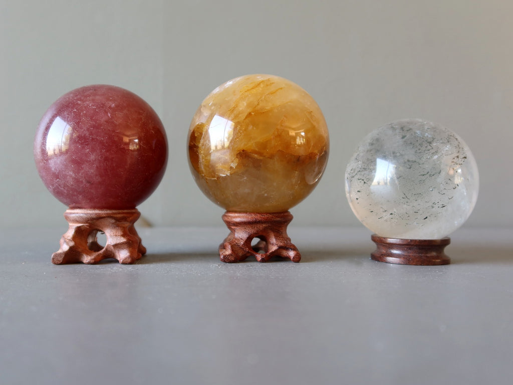 pink, golden, included quartz spheres on wood stands