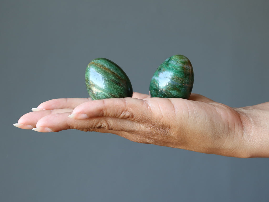 hand holding two green aventurine stone eggs