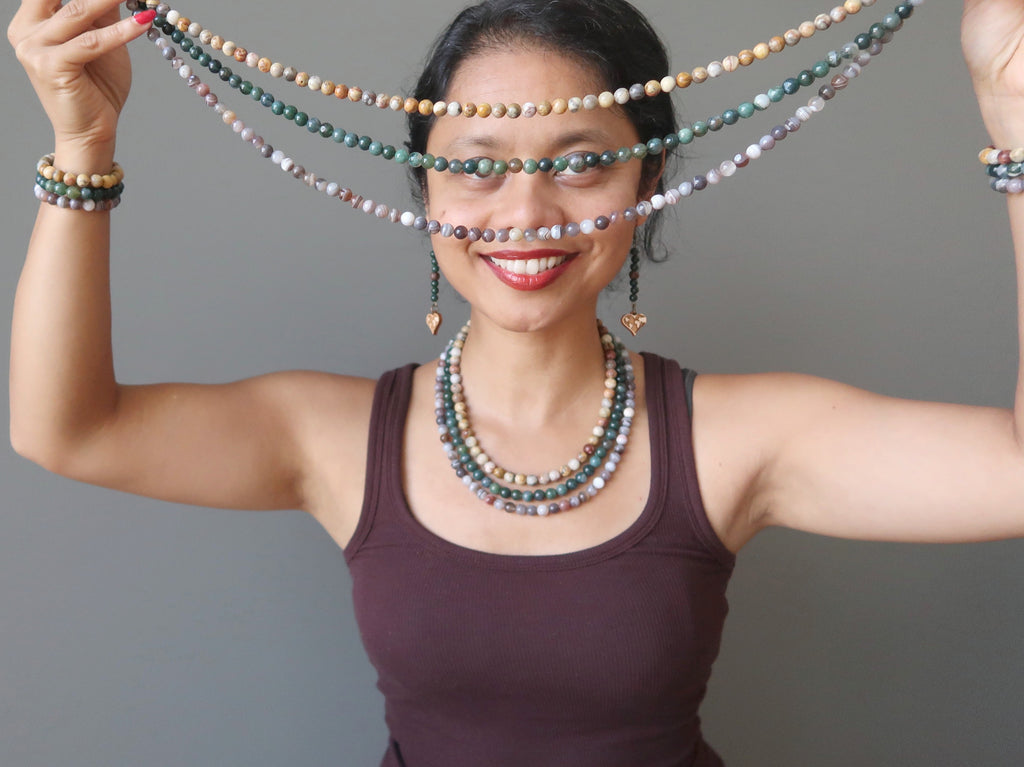 sheila of satin crystals holding up a triple multi-strand agate necklace featuring crazy lace, moss and botswana agate beads.