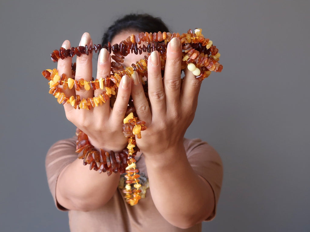 sheila of satin crystals holding up multiple strands of golden baltic amber beaded necklaces