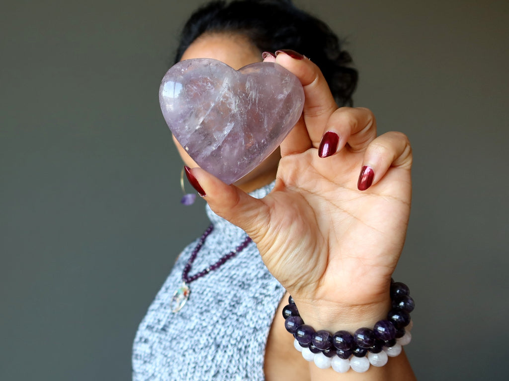 female holding an amethyst heart in front of her face