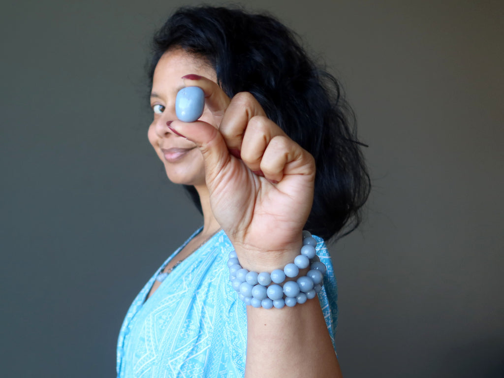 sheila of satin crystals holding up an angelite tumbled stone