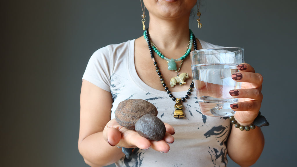 woman holding moqui marbles and glass of water