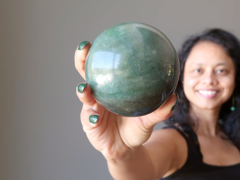 sheila of satin crystals holding out a green aventurine sphere