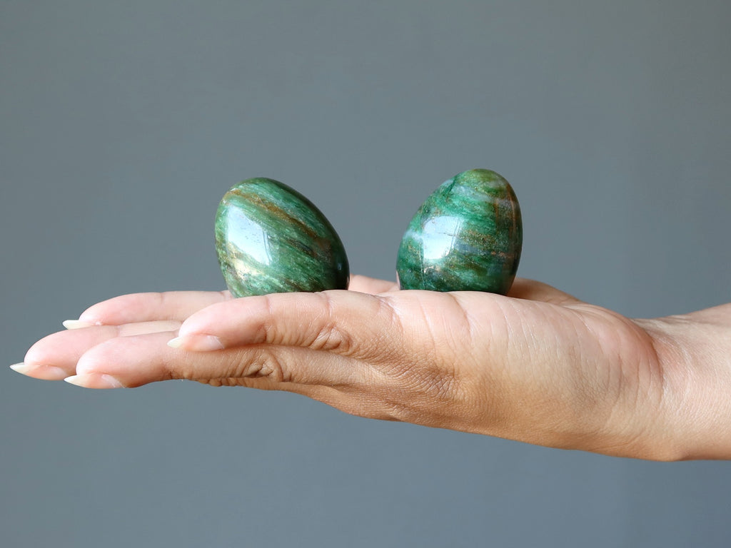 hand holding two green aventurine eggs