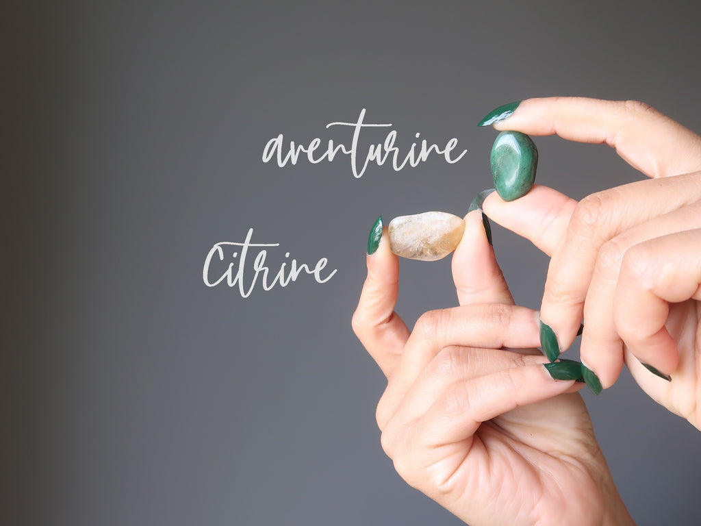 hands holding green aventurine and yellow citrine tumbled stones for abundance crystals