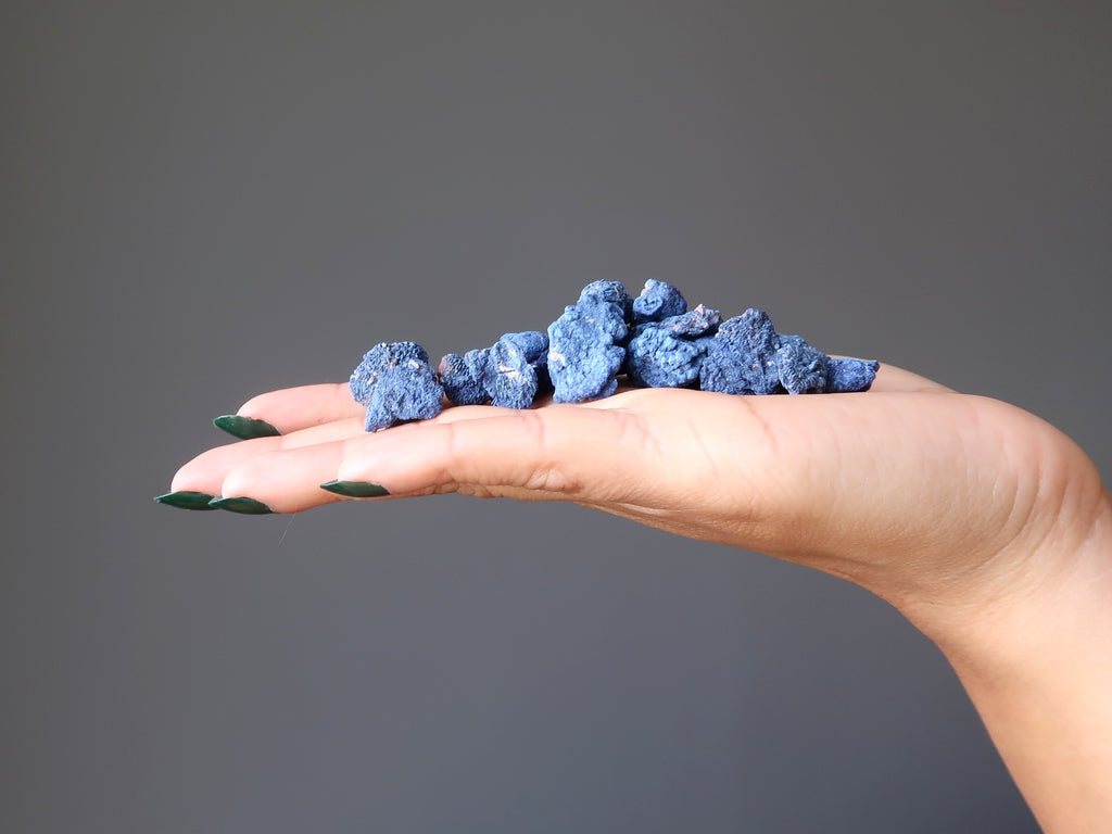 mano che tiene un mucchio di pietre grezze di azurite blu scuro