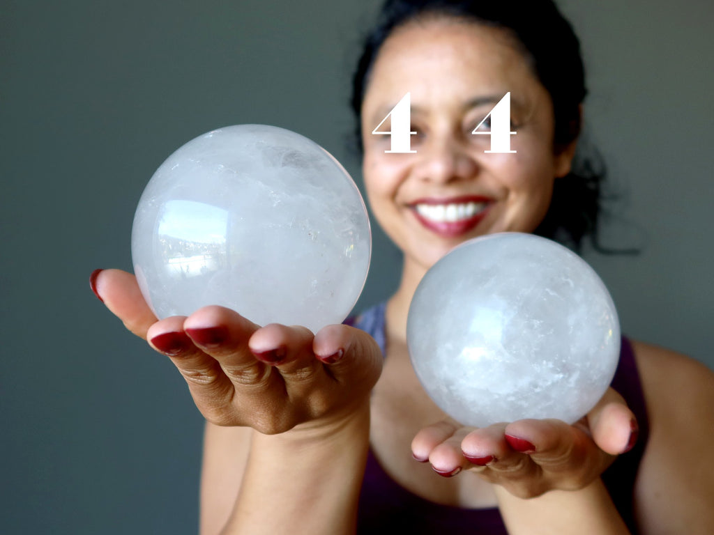 woman with 4's over her eyes holding big quartz crystal balls