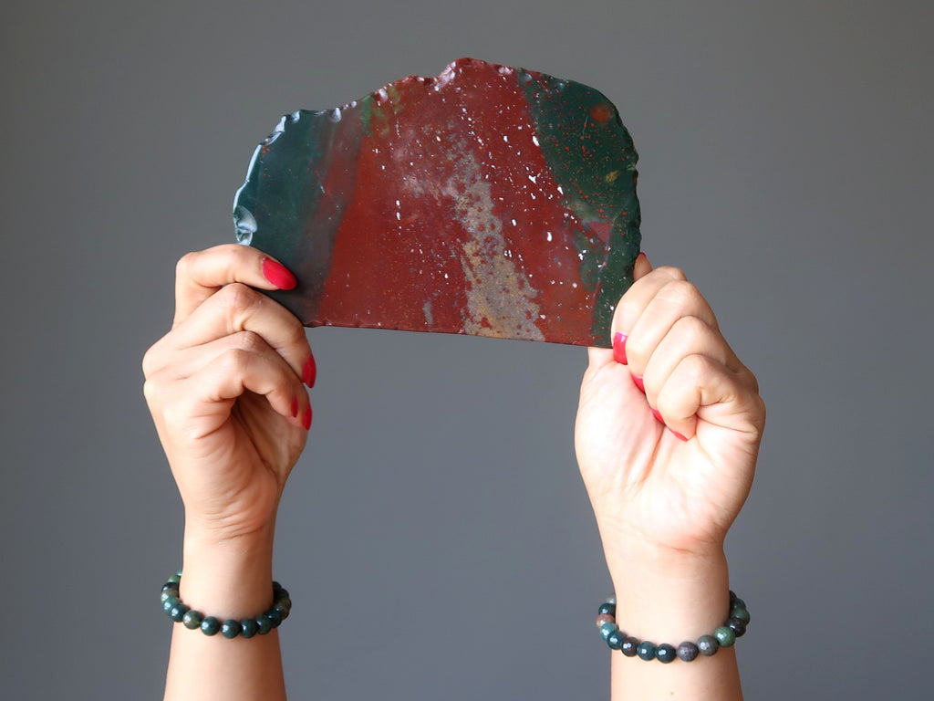 hands holding up a bloodstone slab wearing bloodstone stretch bracelets