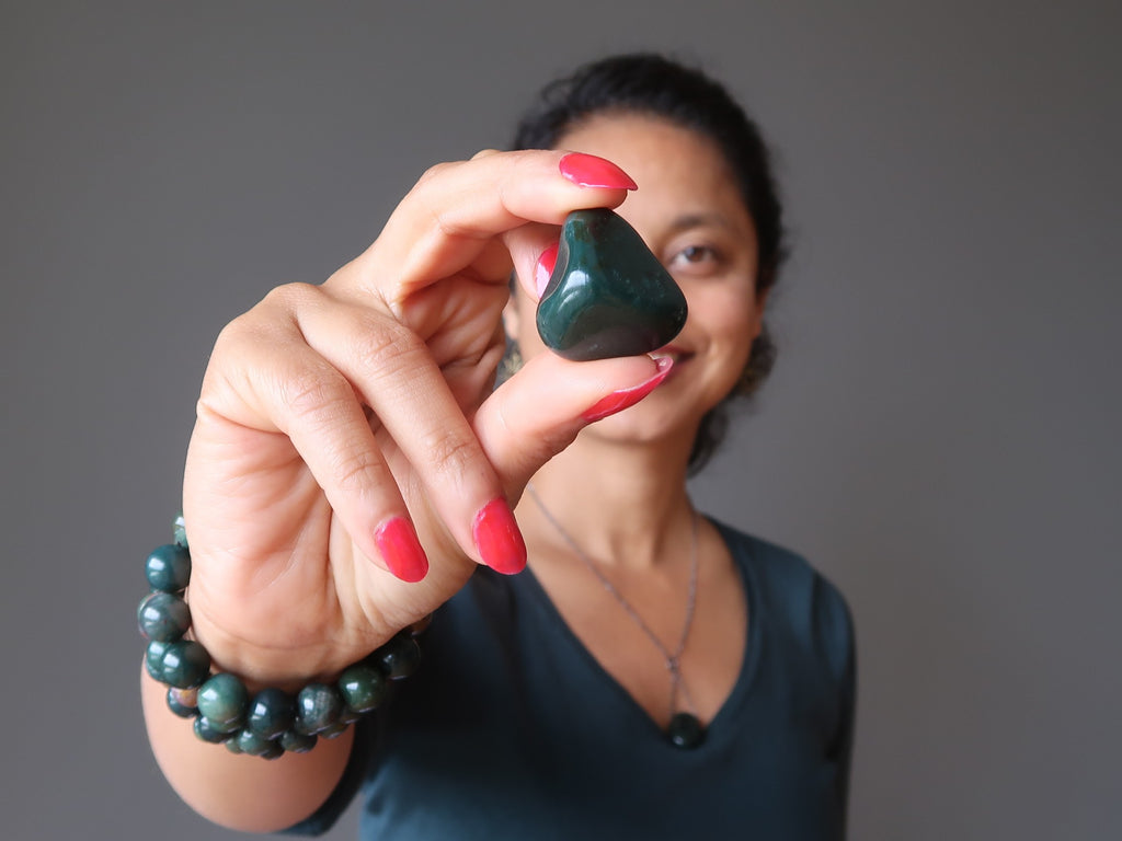 sheila of satin crystals holding up a bloodstone tumbled stone