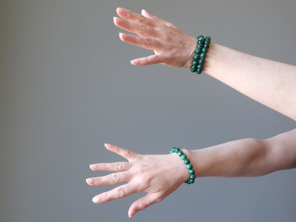 two arms wearing green malachite stretch bracelets