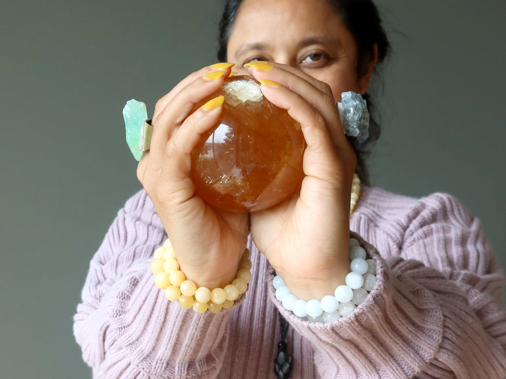 person wearing and holding calcite stones