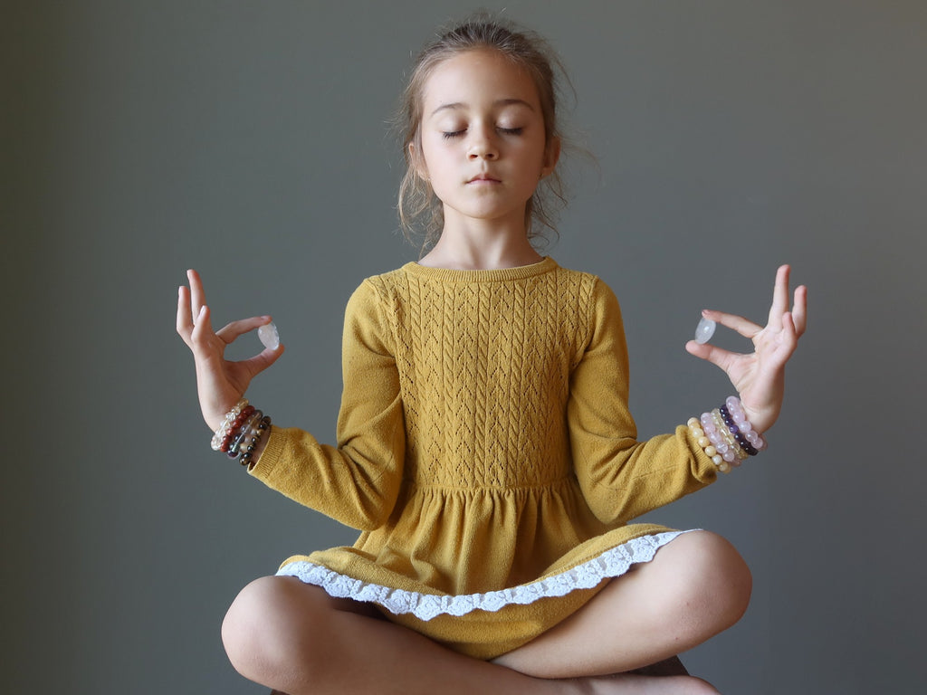 girl meditating with quartz hearts