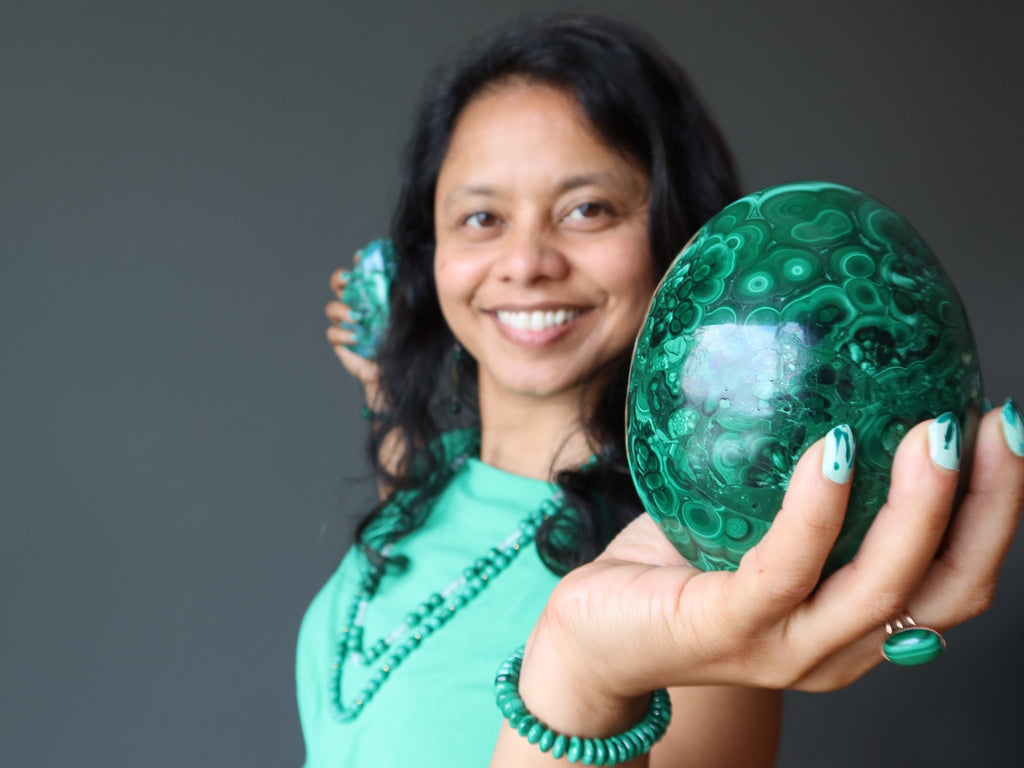 sheila of satin crystals holding a malachite egg and polished stone