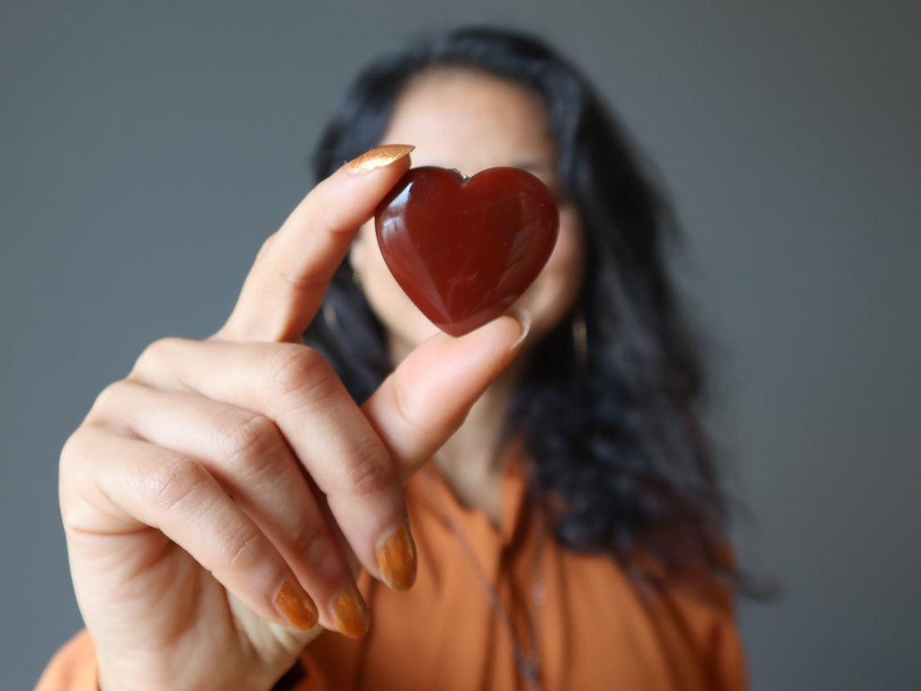 woman with orange carnelian heart in front of her face