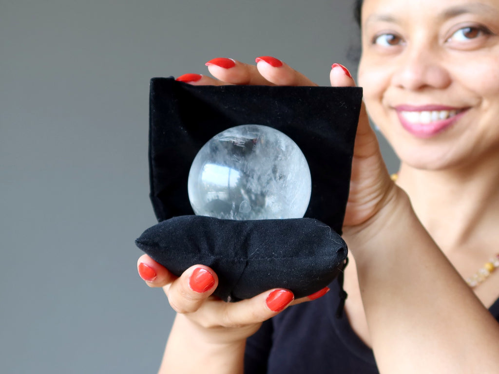 sheila of satin crystals holding a clear quartz ball on a black pillow