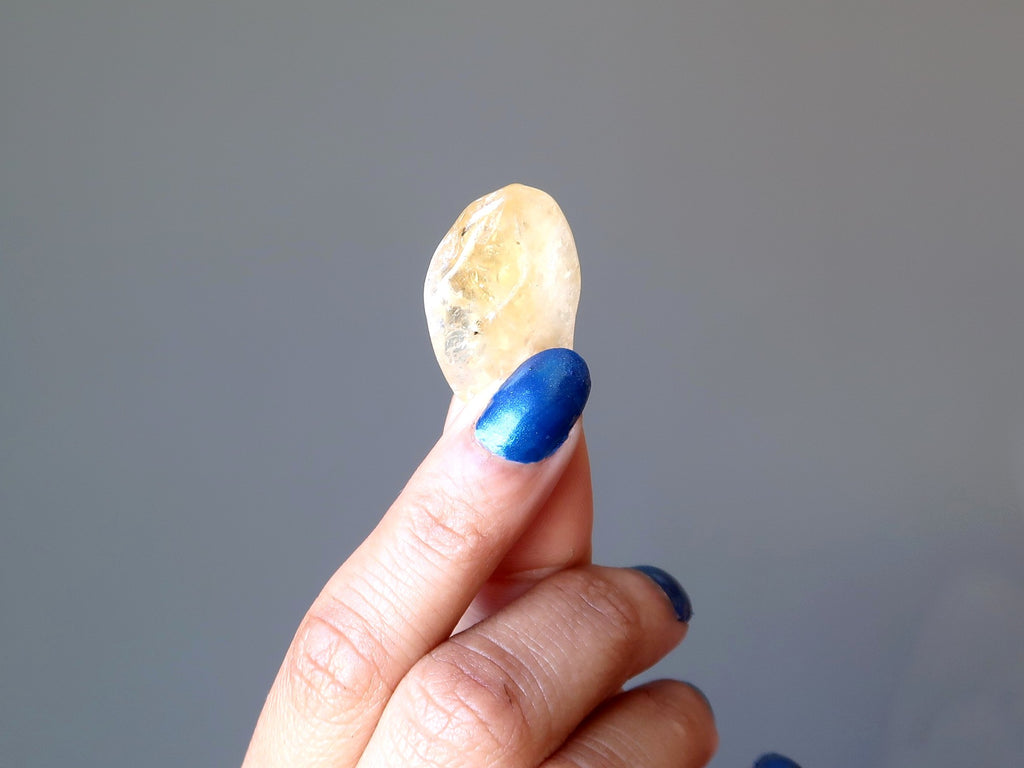 hand holding yellow citrine tumbled stone