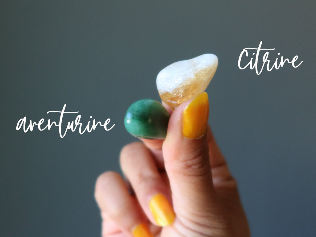 hands holding green aventurine and yellow citrine tumbled stones