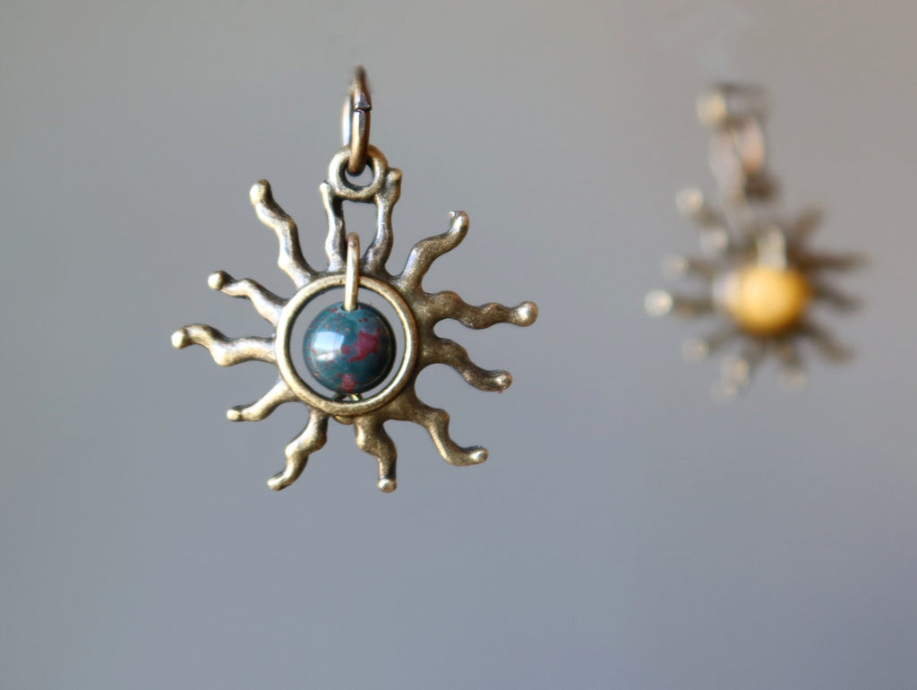 bloodstone sun and yellow jasper sun pendants on gray background