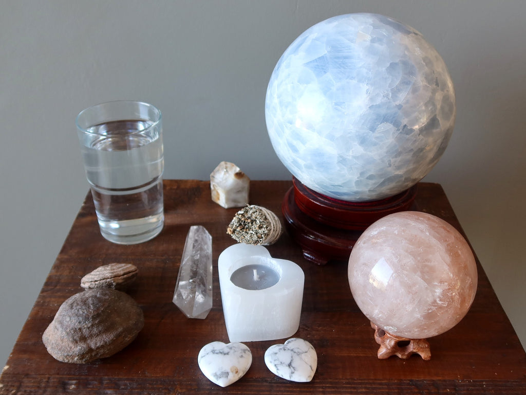 crystals, water, candle, and sage to prepare for a crystal ball gazing session 