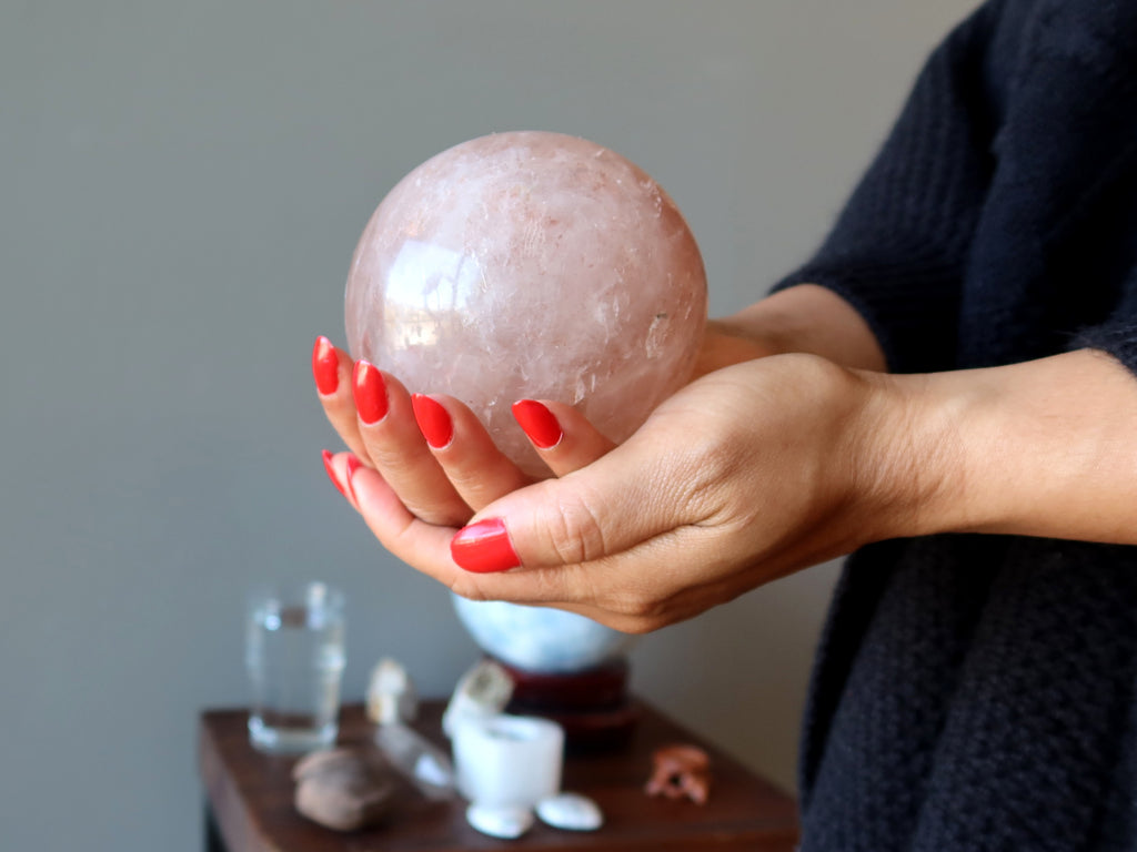 hands holding a red quartz sphere