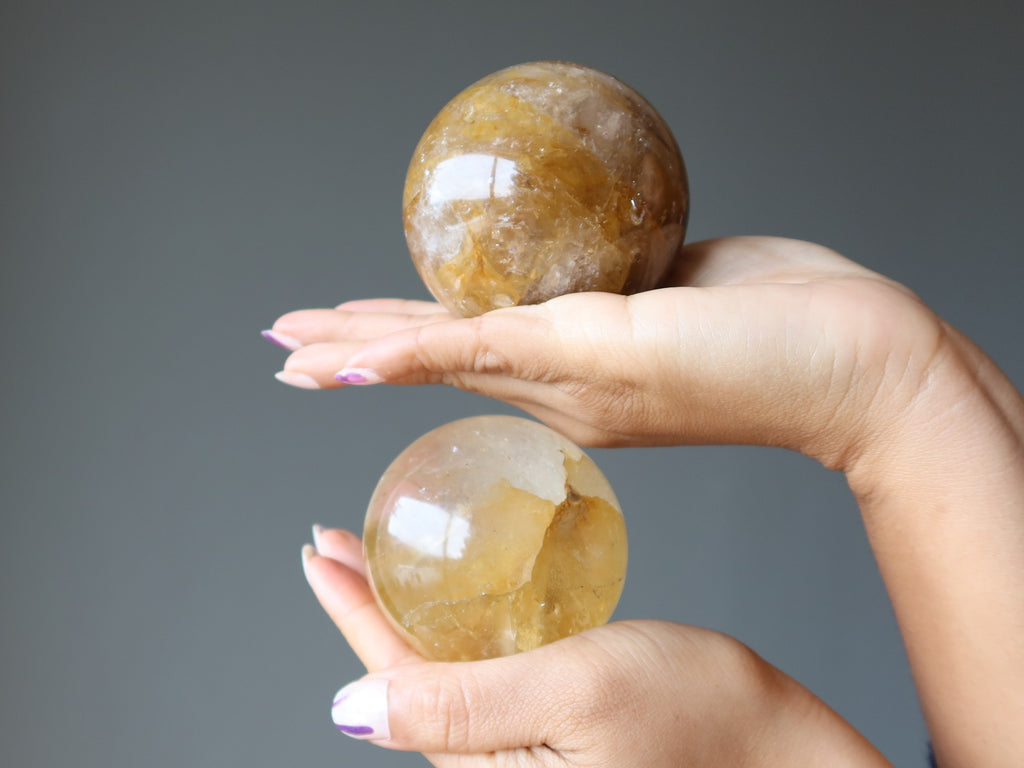 hands holding golden quartz spheres