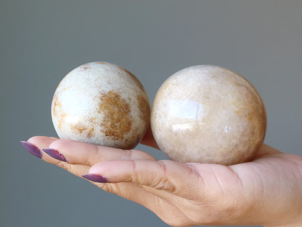 hand holding two citrine spheres