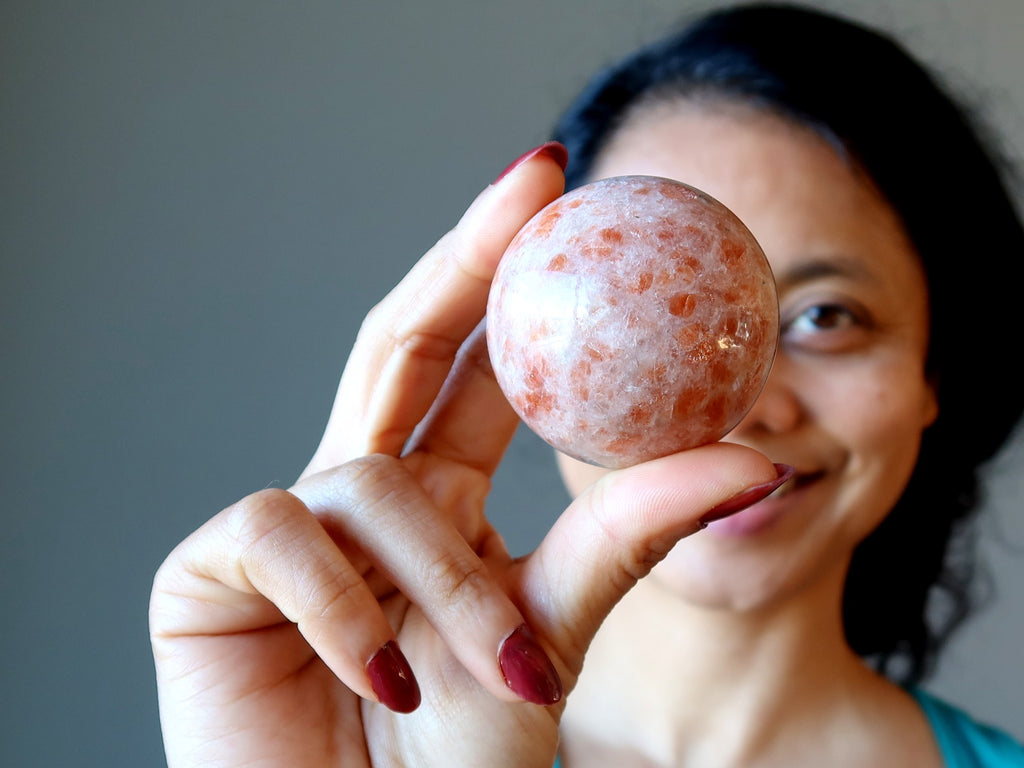 sheila of satin crystals holding up a sunstone sphere