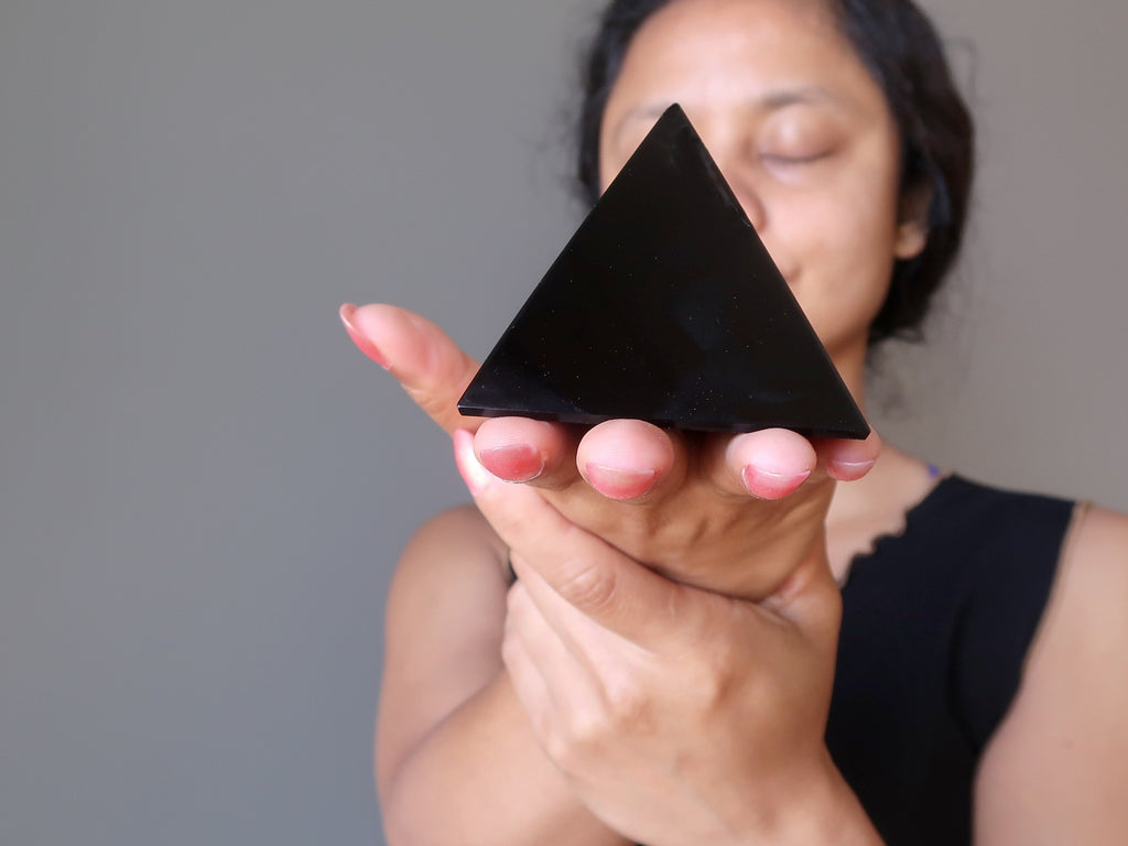 sheila of satin crystals holding a black obsidian stone pyramid