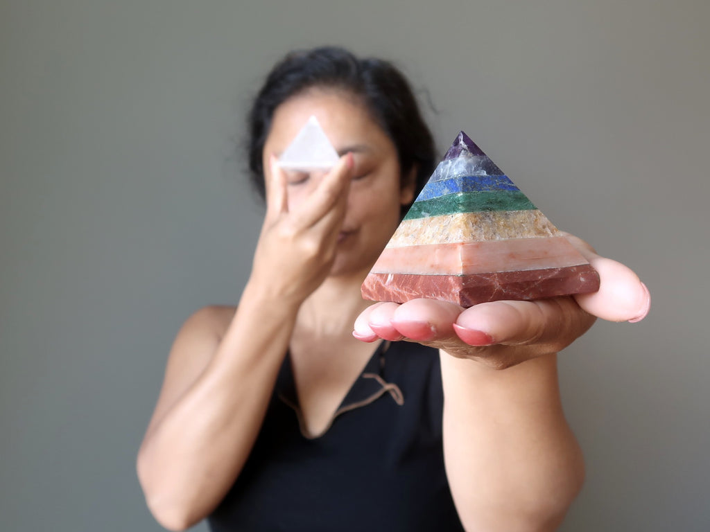 sheila of satin crystals holding up a chakra and a clear quartz stone pyramid
