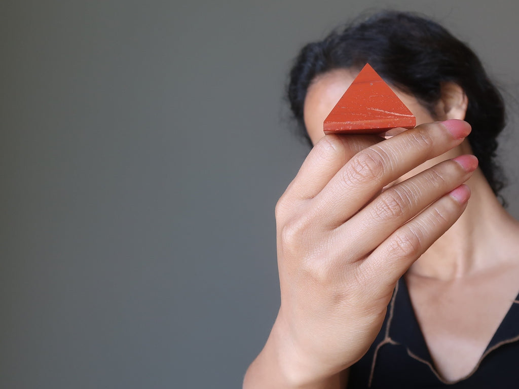sheila of satin crystals holding up a red jasper stone pyramid