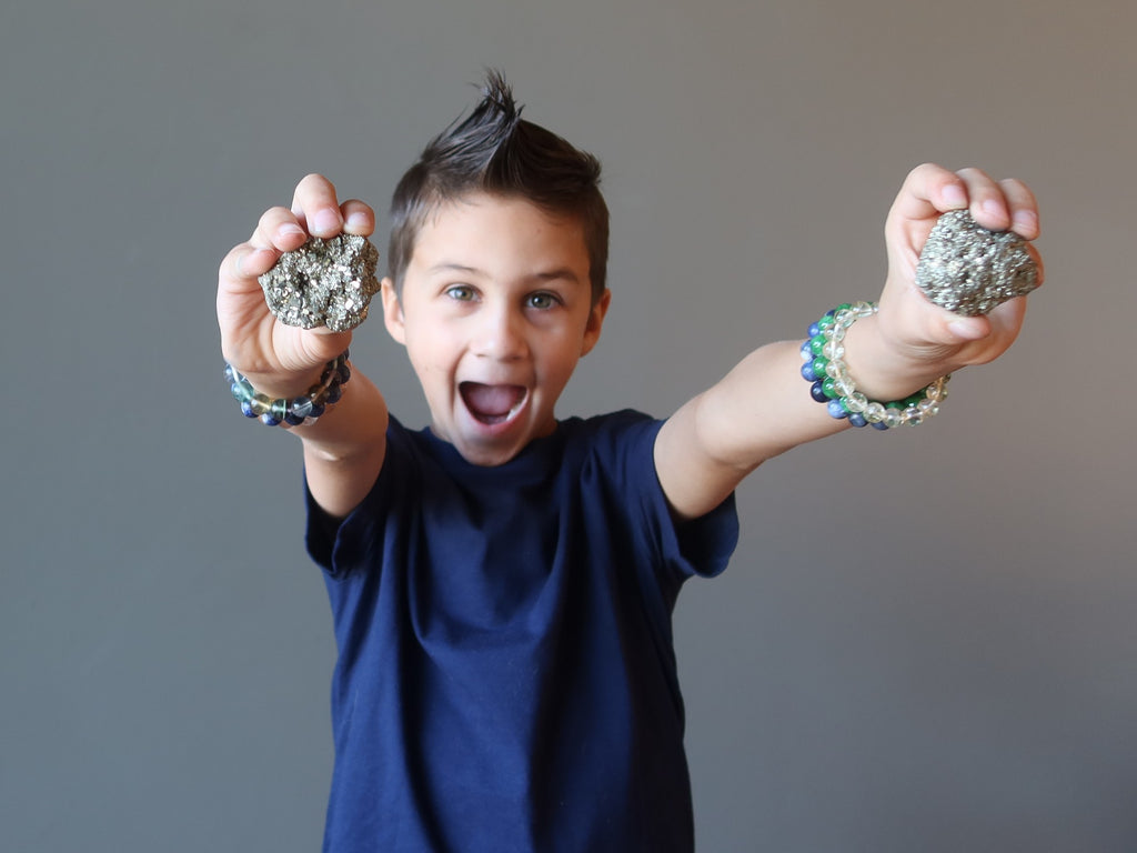 male child holding raw pyrite stones