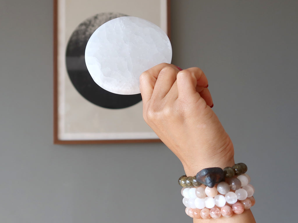 hand wearing stretch bracelets holding selenite circle