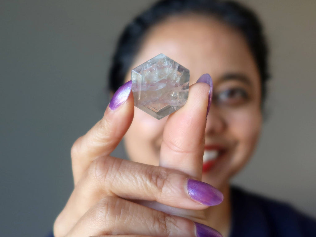 sheila of satin crystals holding up a fluorite hexagon cabochon