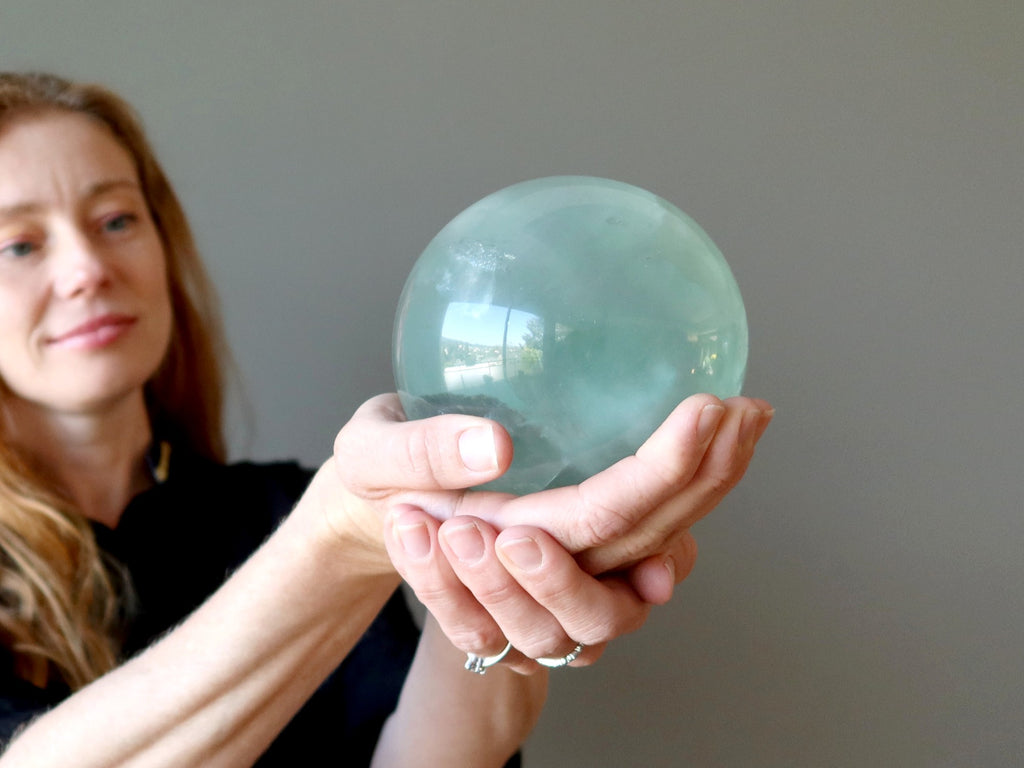 woman holdng green fluorite sphere