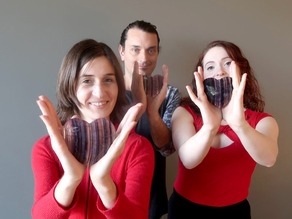 three people holding up crystal hearts