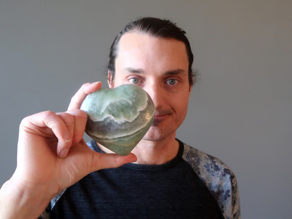 man holding green fluorite heart